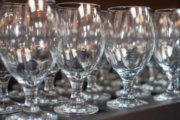 Transparent clean wine glasses aligned neatly on a wooden bar counter for service.