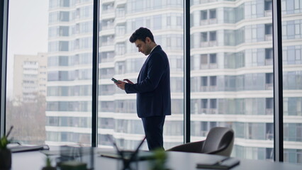 Successful businessman rejoicing message on cellphone emotional in office.