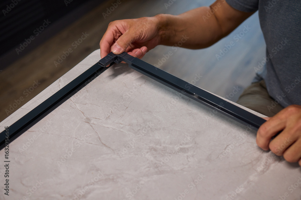 Poster hand assembling a frame on a beautiful and modern table in a creative workspace