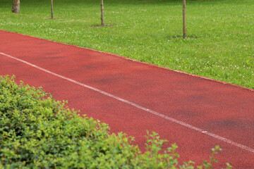 Red running track with white line. Running track in the park with selective focus. Running track surface close-up. Marked white line on the sports field. Background
