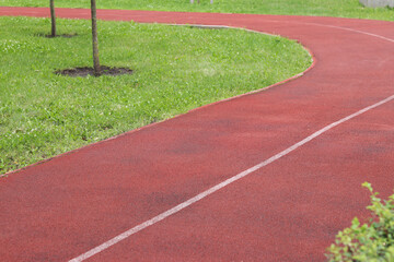 Red running track with white line. Running track in the park with selective focus. Running track surface close-up. Marked white line on the sports field. Background