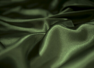 Obraz premium Luxury silk satin matte fabric background. Fashion. Elegant deep shade of green. Vintage. Crumpled material with wavy folds. Cloth canvas texture. Crocodile, olive, pickle, sage, seaweed, fern, moss.