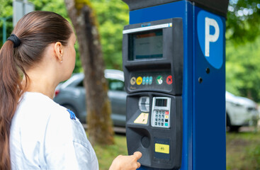 female hand pays for time parking car in street parking meter with solar panels, parking lot,...