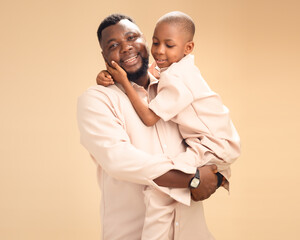 A joyful African father embraces his son warmly, both dressed in matching beige. Set against a soft...