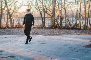 Young man in a black vest holding a wooden frisbee outdoors in a park, ready to play. Casual...