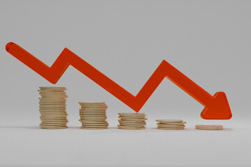 Stacked coins with a red downward arrow symbolizing financial loss, economic crisis, inflation, or...