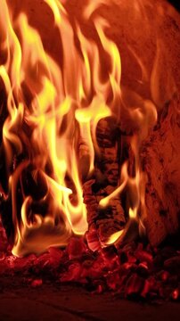 Flames and glowing embers create a rustic and warm atmosphere. Ideal footage for culinary, rustic cooking, pizza oven, or fireplace-related content.