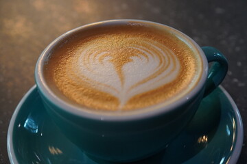 Warm latte art presentation in a teal cup during late afternoon at a cozy cafe
