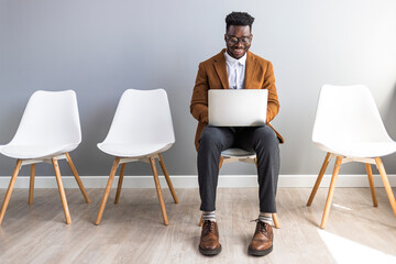 Confident Professional Using Laptop While Waiting in Modern Office Lounge