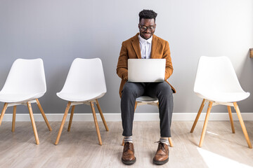 Business Professional Using Laptop While Waiting in a Modern Office Lounge