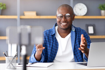 Technology blogger. Mature black man recording video content for his blog in internet, sitting with...