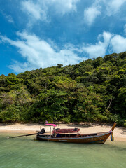 Fototapeta premium Drone shot of a majestic harbor on the Thailand shore beach front, sailboat prepares to navigate along the coastline. Beautiful beach top view showing boat docked in coastal blue waters.