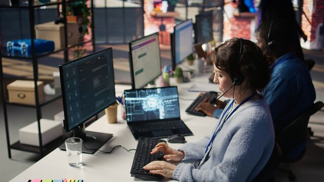 Call center worker in office uses AI LLM assistant to reply to customer queries. Woman doing customer service job generating automated responses to clients using artificial intelligence tech, camera B - Powered by Adobe