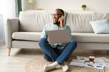 Always In Touch. Black Freelancer Man Talking On Phone Using Laptop Working Remotely From Home,...