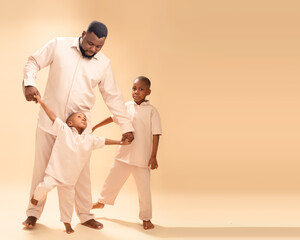 Bathed in soft light, a father meets his sons’ gaze with quiet pride. Barefoot and in matching...