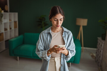 Happy woman using smart phone at home: smiling while reading good news