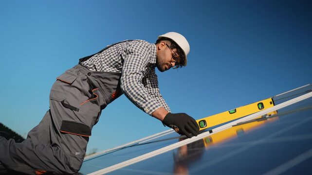 Muslim technician installing and leveling solar panels on rooftop