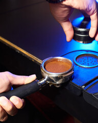 Close-up of a portafilter with tamped coffee grounds, ready for brewing, placed on a professional...
