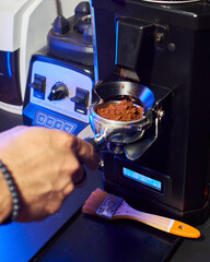 Close-up of a barista adjusting freshly ground coffee in a portafilter, with dynamic motion as the grounds settle from the grinder