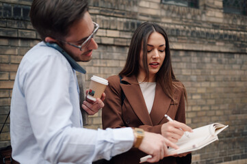 Business people discussing work outdoors while drinking coffee