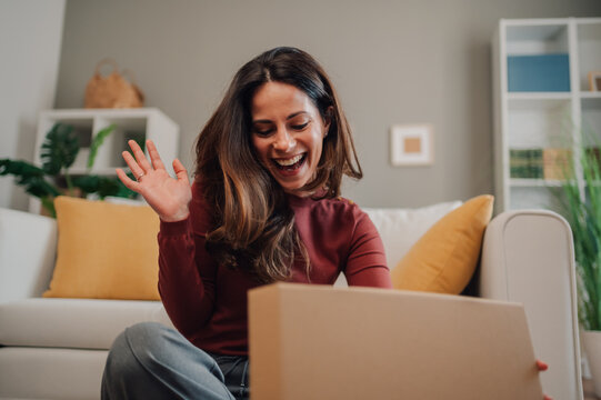 Happy woman unboxing package and waving at home