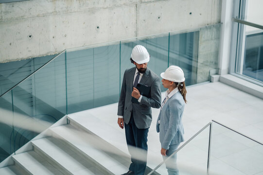 Architects discussing blueprint in modern building using tablet - Powered by Adobe