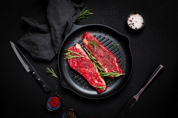 Raw beef sirloin steaks on grill pan, ready for cooking. Black background, top view