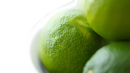 Close up of vibrant green limes in a white bowl with a dark background highlighting their textured skin and freshness