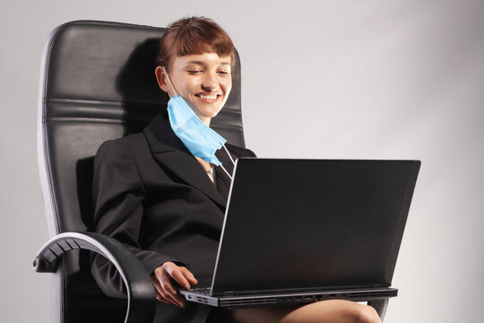 Young businesswoman smiling with face mask on neck working on laptop