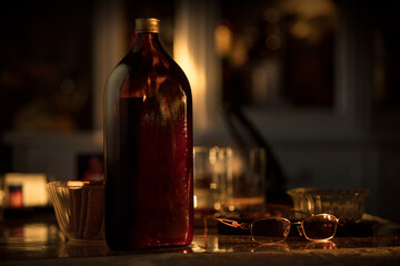 A very large, dark bottle of syrup or other dietary supplement from a home medicine cabinet. An unlabeled bottle sits on a table at home at sunset. Elderly health.