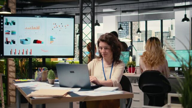 Focused administrator immersed in data analysis and strategic planning, sitting alone at her workstation. Her vision and goals oriented mindset provide success to multinational company. Camera A.