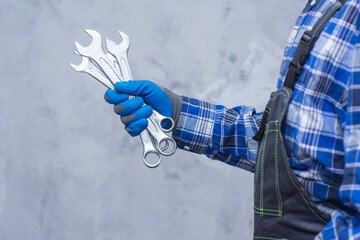 Mechanic holding metal wrenches in gloved hand. Automotive tools, car repair concept and mechanic...