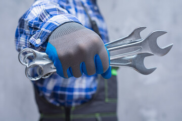 Mechanic holding metal wrenches in gloved hand. Automotive tools, car repair concept and mechanic...