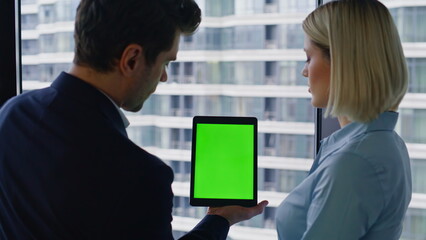 Colleagues discussing mockup tablet data standing together in office closeup.