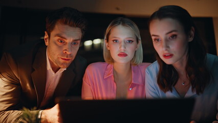 Business partners surprised news at laptop working at night workplace closeup. 