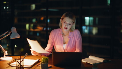 Employee dissatisfied late work reading documents in lamp light closeup. 