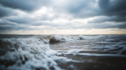 Naklejka premium Crashing ocean waves beneath a dramatic overcast sky are seen