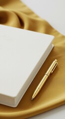 Gold pen and white planner on mustard silk