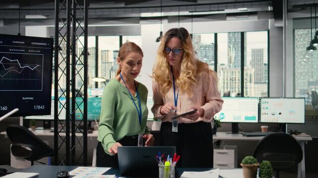Determined team of professional women assembling to review charts and data projections, illustrating their collaborative mindset to guarantee strategic analysis for measurable success. Camera A.