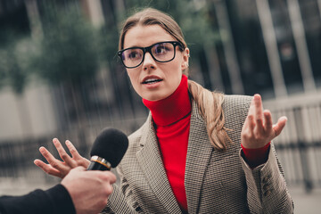 Professional lady being interviewed outdoors wearing a formal jacket and showcasing confidence in a...