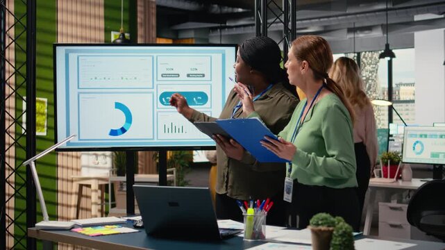 Collaborative team of professional women reviews key data and reports while setting strategy for business growth, aligning insights with development goals and teamwork. Networking. Camera A.