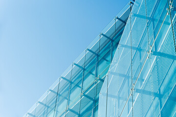 Contemporary architectural structure featuring a blue glass facade with metal framework under clear...