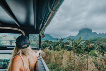 Tourist enjoying a scenic 4x4 safari adventure through lush jungle with a view of Mount Rotui,...