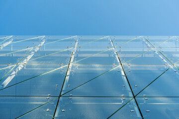 Contemporary building facade featuring large glass panels, metal fasteners, and geometric lines...
