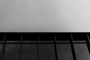 Black and white photo showing the upper section of a modern glass building with strong vertical...