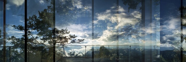 Dramatic sky and landscape viewed through fragmented glass panels, creating a layered and reflective panoramic vista of nature and urban horizon