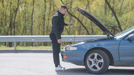 Caucasian man checking engine oil level in his car. 