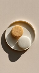 Two round sponges on a pale beige plate