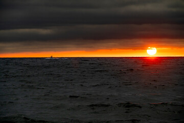 Sailboat in the distant horizon with dramatic sky