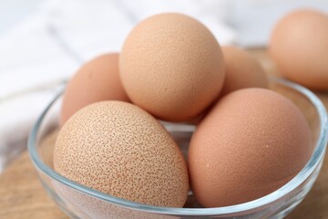 Raw chicken eggs in bowl on table, closeup
